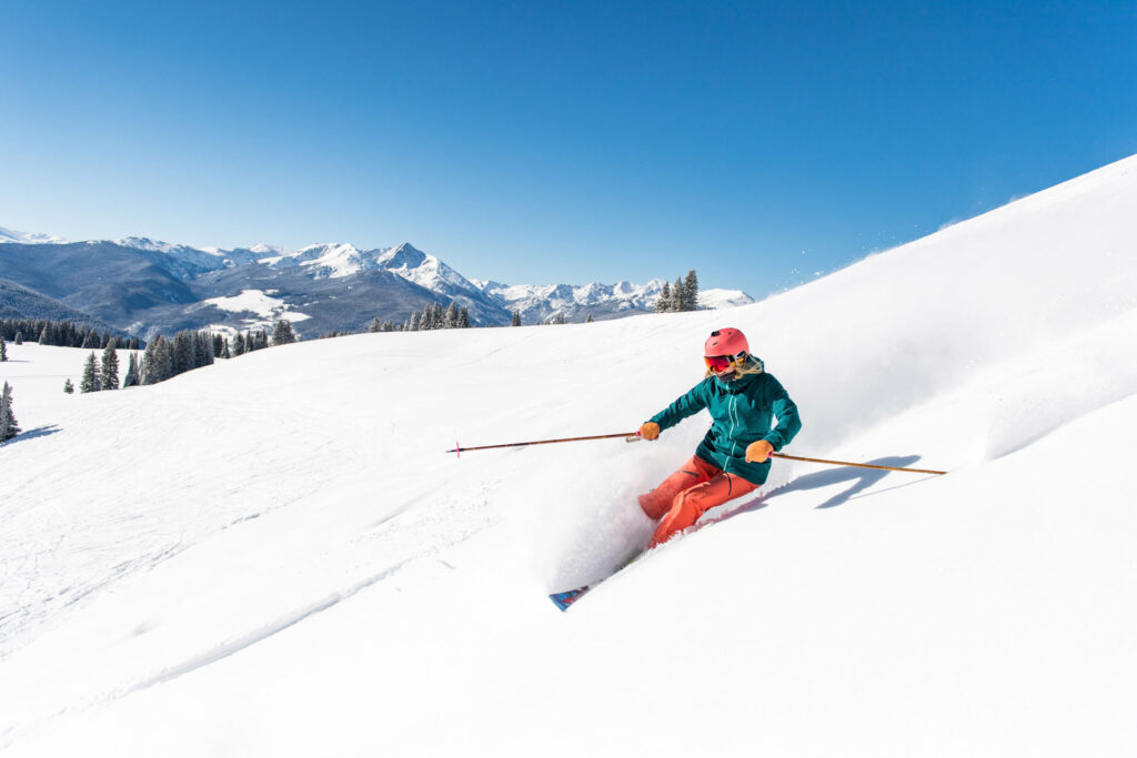 Female skier skiing in powder in the Vail Back Bowls on sunny day